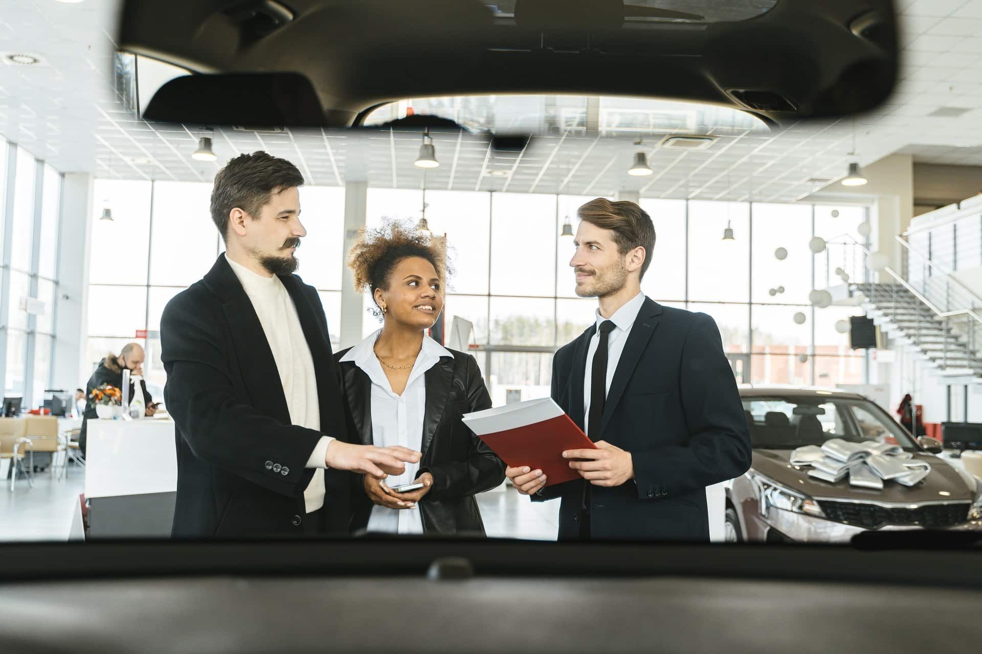 Ein Paar wird in einem Autohaus von einem Verkäufer beraten.